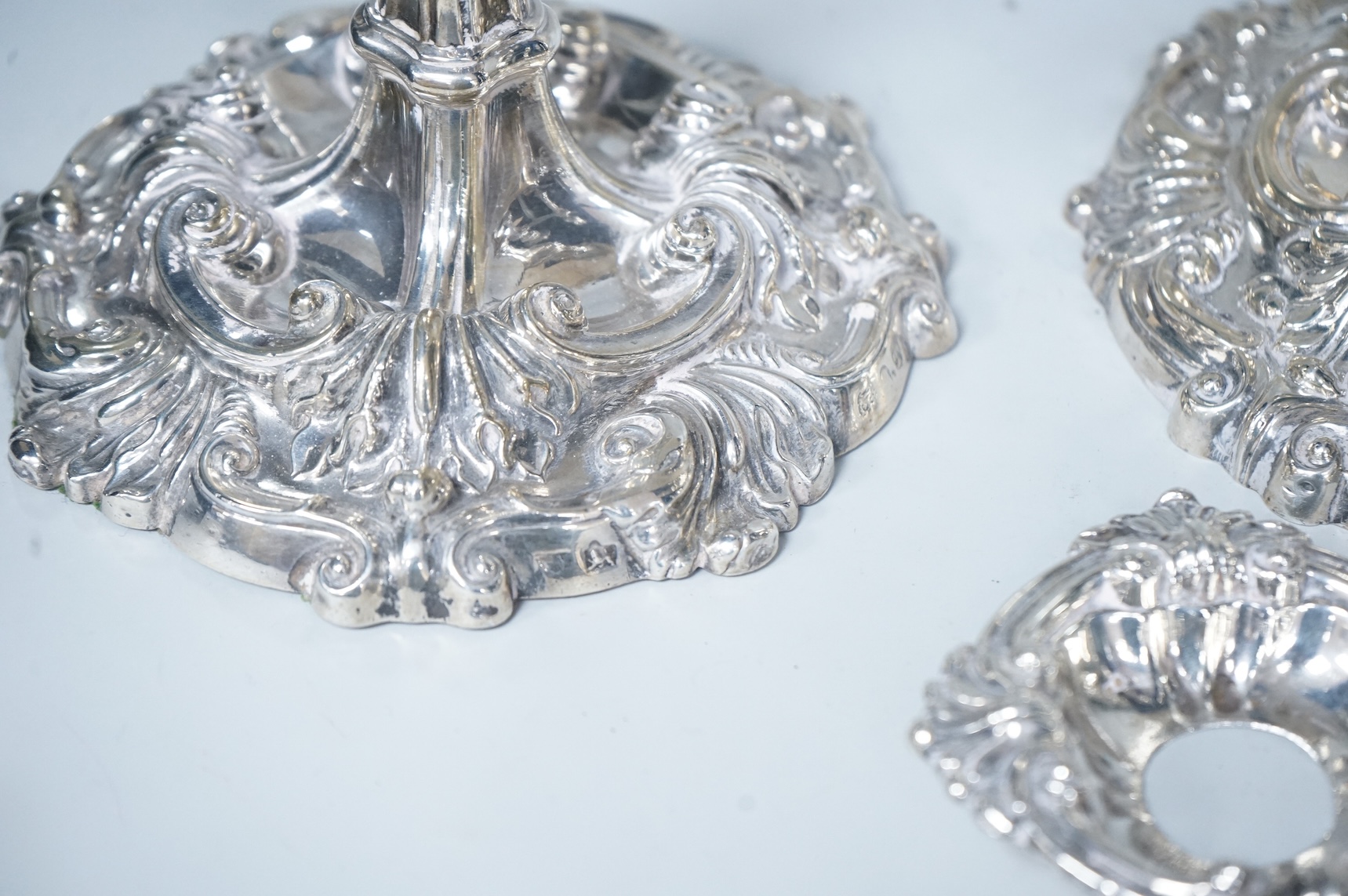 Two similar pairs of George III silver candlesticks, both with fluted tapered columns and decorated with foliage and scrolls, fixed sconces, makers mark rubbed, Sheffield, 1814 and S.C. Younge & Co, Sheffield, 1816, 28.5